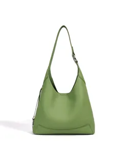 Gros plan des details du sac porte epaule en cuir vert avec texture fine et anneau metallique.