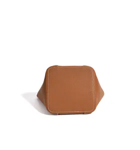 Vue détaillée du fond d'un sac seau en cuir marron avec de fines coutures blanches.