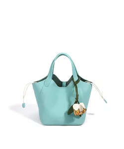 Gros plan sur les détails du sac seau en cuir bleu clair doté d'un charmant pendentif floral élégant.