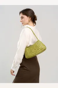 Detailed shot of a green woven leather underarm shoulder bag worn by a model against a clean backdrop.