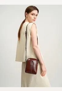 Close-up of dark brown leather crossbody phone bag, fine strap and metallic detail.