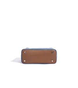 Détail rapproché du fond de sac à main associant cuir marron durable et tissu denim bleu.