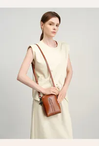 Brown leather phone crossbody bag closeup showing fine texture and sleek metal buckle detail.