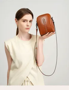 Detailed view of the brown leather crossbody phone bag, showcasing fine texture and hardware.