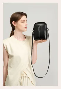 Minimalist black leather phone crossbody bag detail view, showing delicate hardware and texture.