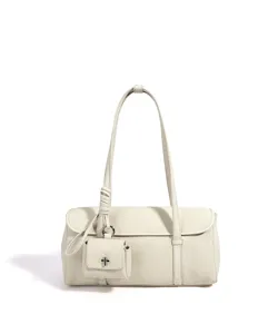 Nahaufnahme der weißen strukturierten Leder-Baguette-Umhängetasche mit Mini-Taschen-Anhänger.
