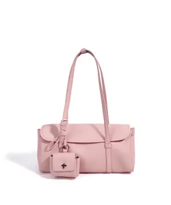 Rosa leder baguette umhängetasche detail mit feiner lychee textur und hängendem anhänger.
