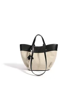 Canvas and leather tote bag detail, featuring color-block design, handles, and hanging charm.