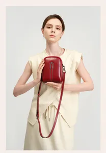 Detail view of wine red genuine leather phone crossbody bag, showcasing fine stitching and metal clasp.
