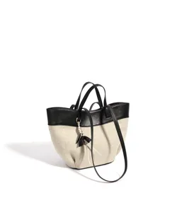 Canvas and black leather contrast tote bag detail view, showing exquisite stitching and charm.