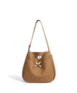 Detalle de bolso hobo de cuero marrón bajo el brazo, elegante herraje de cerradura.