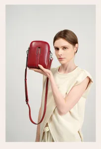 Detailed view of red leather crossbody phone bag, elegant stitching and metal hardware.