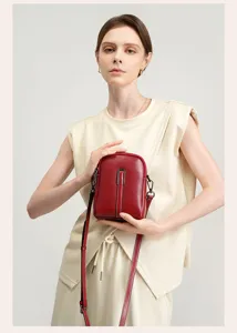 Close-up detail of a chic red leather mini crossbody phone bag, elegant metal hardware and strap.