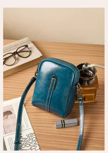Close-up view of a stylish dark blue genuine leather crossbody phone bag with fine strap.