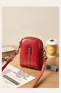 Detail view of a stylish red genuine leather crossbody phone bag with multi-zipper compartments.