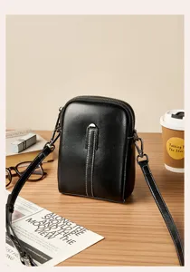 Detail view of a black genuine leather crossbody phone bag with double zipper and metal lock.