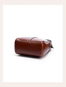 Detail shot of the brown leather phone crossbody bag, highlighting bottom structure and stitching.