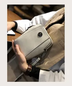 Close-up detail of the stylish white wax leather phone bag, showing fine texture and zipper.