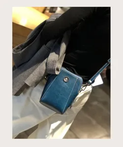 Dark blue wax leather small crossbody phone bag with retro metal button and chic white stitching details.