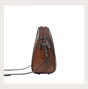 Genuine leather crossbody bag detail view, brown oil-wax cowhide texture with double zippers.