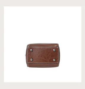 Detailed bottom view of brown genuine leather women crossbody bag with metal feet.