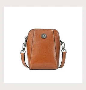 Detailed view of the brown oil-wax leather mini crossbody bag featuring a chic metallic floral charm.