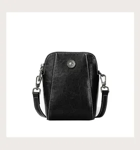 Black waxed cowhide phone crossbody bag detail, featuring metal flower and neat white stitching.