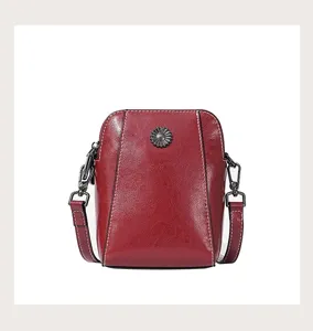 Red oil-wax leather crossbody phone bag detail, with fine stitching and retro metal flower decor.