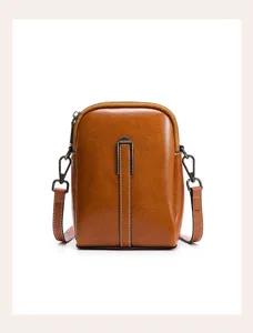 Detailed view of the brown leather mini crossbody phone bag with metal hardware and zipper.