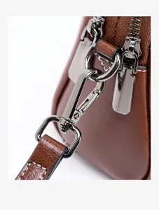 Brown leather women crossbody bag detail view showing metal zipper and clasp hardware.