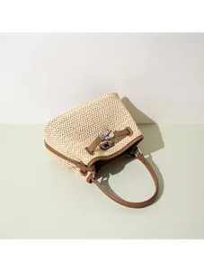 Woven straw handbag detail showing brown leather trim and metal turn-lock closure.