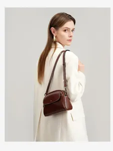 Detailed view of the vintage brown leather shoulder bag worn by the model in lifestyle scene.