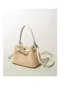 Close-up detail of woven straw bucket bag with white leather trim and metal lock closure.