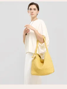 Detail view of yellow woven shoulder tote bag, handcrafted leather texture and stylish look.