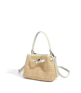 Close-up detail of the woven straw bucket bag featuring light leather trim and metal lock closure.