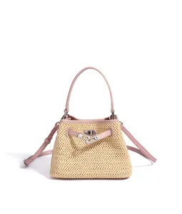 Detailed view of straw woven handbag with pink leather trim and metal turn-lock closure.