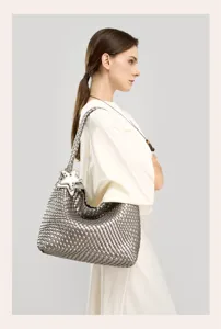 Close-up detail of silver woven leather shoulder bag with star charm and premium craft.