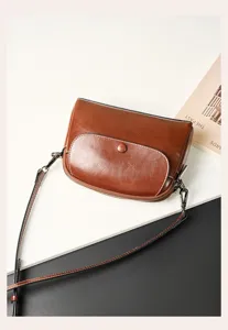 Close up detail of retro brown leather shoulder bag showing fine stitching and metal hardware.