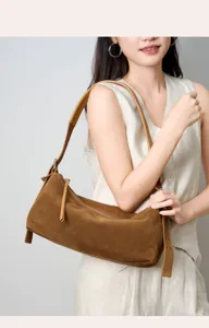 Primo piano di un'elegante borsa a tracolla in camoscio marrone, che mostra consistenza e tracolla.