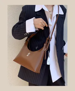 Detailed view of the brown leather shoulder bag featuring a chic metal lock and elegant strap design.