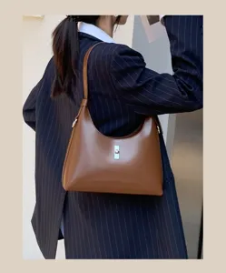 Close-up detail shot of brown genuine leather underarm shoulder bag with metal turn-lock.