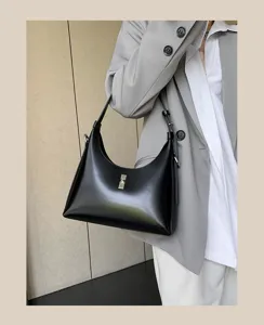 Close-up of a stylish black leather hobo shoulder bag with metal turn-lock closure detail.