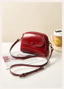 Red leather cross-body bag detail, featuring retro flap design and fine adjustable strap.
