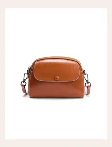 Brown leather crossbody bag detail view featuring zip closure and retro shoulder strap hardware.