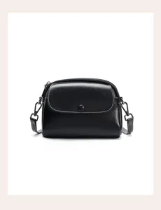 Black leather women's shoulder crossbody small round bag detail view with white stitching.
