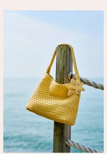Stunning yellow woven hobo shoulder bag featuring star charms in a scenic seaside view.