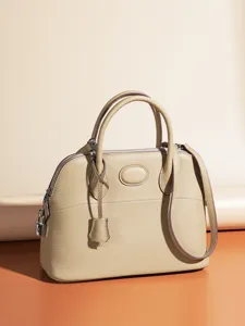 Classic leather dome shoulder bag for women, elegant beige top handle handbag with padlock.