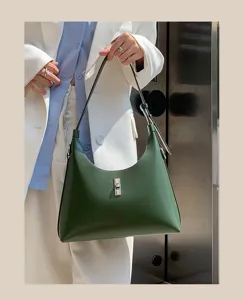 Detailed view of dark green leather shoulder bag with chic metal turn lock and underarm strap.