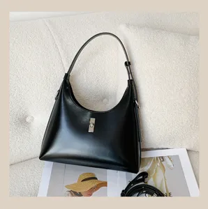 Close-up detail of the black leather hobo shoulder bag showing metal lock and smooth texture.