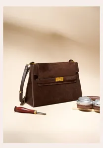Detailaufnahme der braunen Wildleder Umhängetasche mit edlem Metallverschluss und Textur.